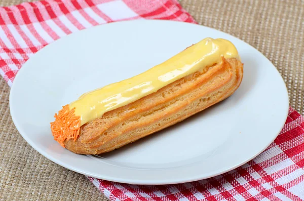 Éclair met een crème op een plaat — Stockfoto