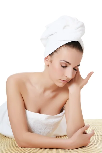 De mooie vrouw in een handdoek op bamboe tapijt. Spa concept. — Stockfoto