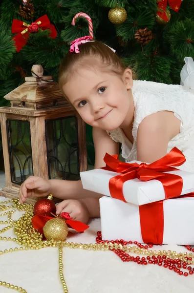 A menina em uma árvore de pele de Natal com presentes — Fotografia de Stock