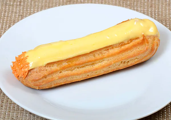 Eclair com uma nata em uma chapa — Fotografia de Stock