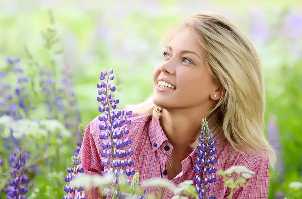 Красивая женщина в поле с Люпеном — стоковое фото