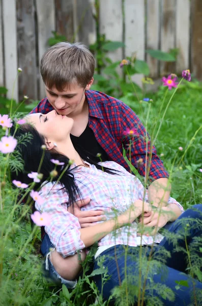 Αγαπητική νεαρό ζευγάρι στο πεδίο με λουλούδια — Φωτογραφία Αρχείου