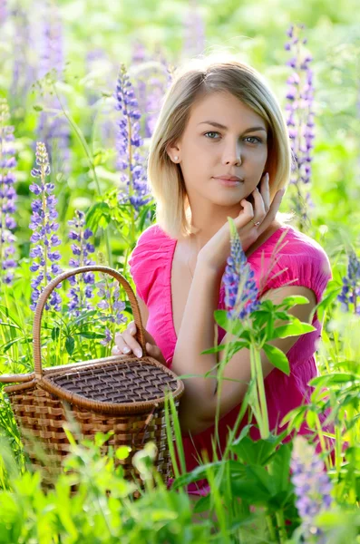 A bela mulher no campo com lupin — Fotografia de Stock