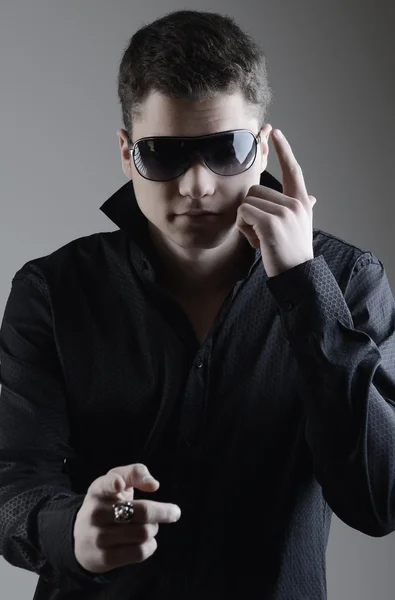 Mode portret van jonge man in zwarte shirt houdingen over muur — Stockfoto