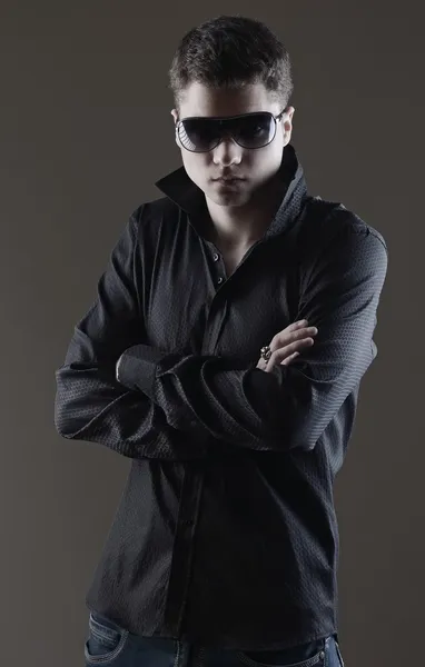 Retrato de moda de hombre joven con camisa negra posa sobre la pared — Foto de Stock