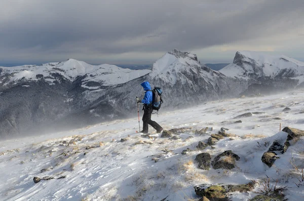 Un hombre caminando en las montañas de invierno en un clima tormentoso —  Fotos de Stock