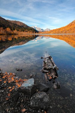 bir günlük ve berrak sonbahar dağ gölü ile uzak tepeleri yansıması kayalarda