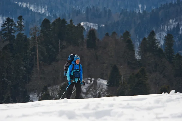 Kvinnlig backpacker klättrar en kulle i bergen på vintern — Stockfoto