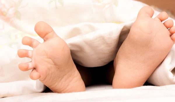 赤ちゃんの足が毛布の下 — ストック写真