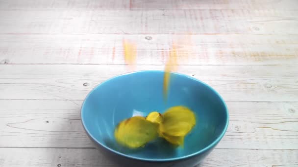 Картофельные Чипсы Падают Голубую Керамическую Чашу Стоящую Белом Деревянном Столе — стоковое видео