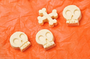 Cadılar Bayramı şekerleri kafatasları ve kemikler turuncu kağıt üzerinde şeker şekerler. Tatil ikramiyeleri.