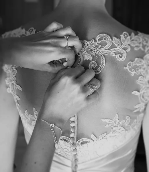 Demoiselle d'honneur attacher des boutons sur la robe de mariée — Photo