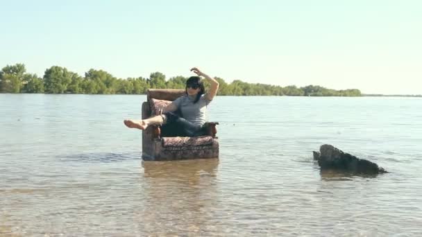 Chica sentada en una silla, de pie en el agua — Vídeo de stock