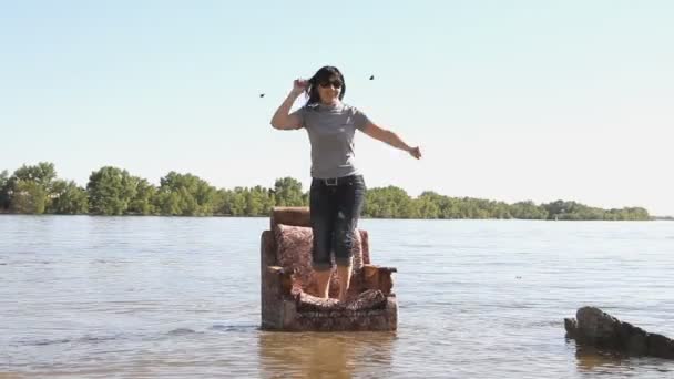 Chica sentada en una silla, de pie en el agua — Vídeos de Stock