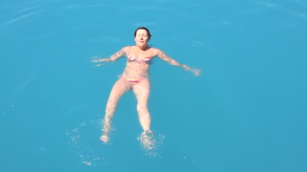 Молодая женщина плавает в синем море — стоковое видео