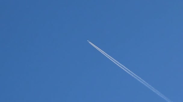 Следы самолета на фоне голубого неба — стоковое видео