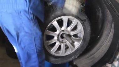 Mechanic repairman making wheel balancing on the machine tool
