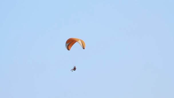 Parapente sobre as montanhas contra o céu azul claro — Vídeo de Stock