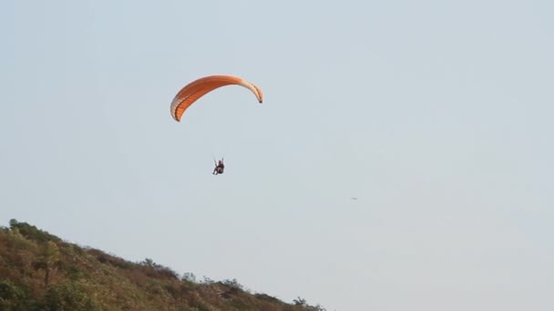 Parapente sobre as montanhas contra o céu azul claro — Vídeo de Stock