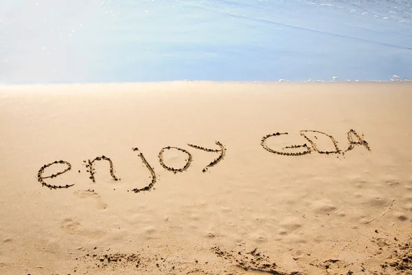 De woorden genieten van goa geschreven in het zand op een strand — Stockfoto