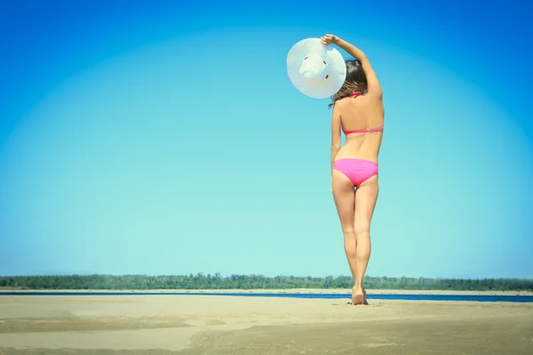 समुद्र तट पर सफेद टोपी के साथ गुलाबी बिकिनी में महिला — स्टॉक फ़ोटो, इमेज