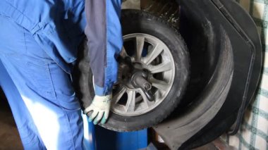 Mechanic repairman making wheel balancing on the machine tool