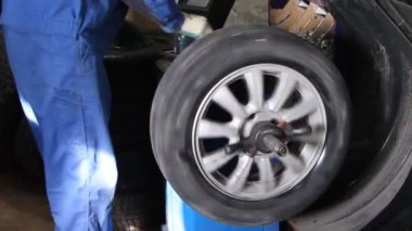 Mechanic repairman making wheel balancing on the machine tool