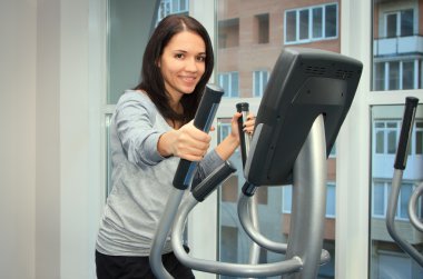 young woman doing exercise on a elliptical trainer clipart