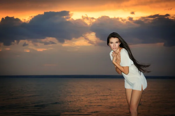 夕日の光線で海の近くのきれいな女性の立っています。 — ストック写真