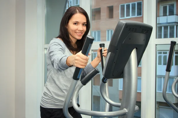 Junge Frau turnt auf einem Crosstrainer Stockbild