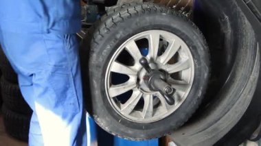 Mechanic repairman making wheel balancing on the machine tool