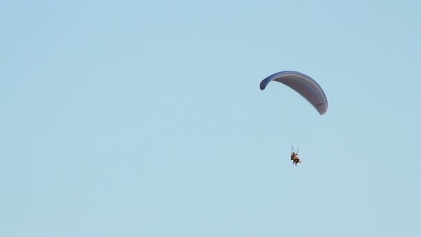 Parapente sobre as montanhas contra o céu azul claro — Vídeo de Stock