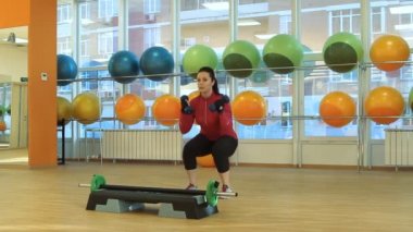 Dambıllarla egzersiz yapan genç bir kadın.