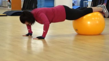 fit ball ile egzersiz yaparak genç bir kadın