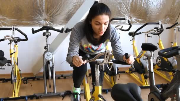 Жінка займається тренуванням на кардіо-велосипеді — стокове відео
