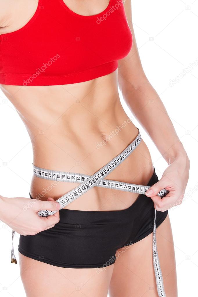 Woman measuring waist with a tape measure, isolated on white