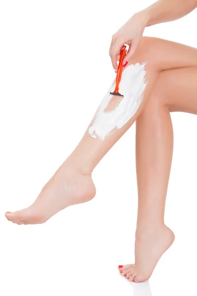 Kvinna rakar benen, vit bakgrund — Stockfoto