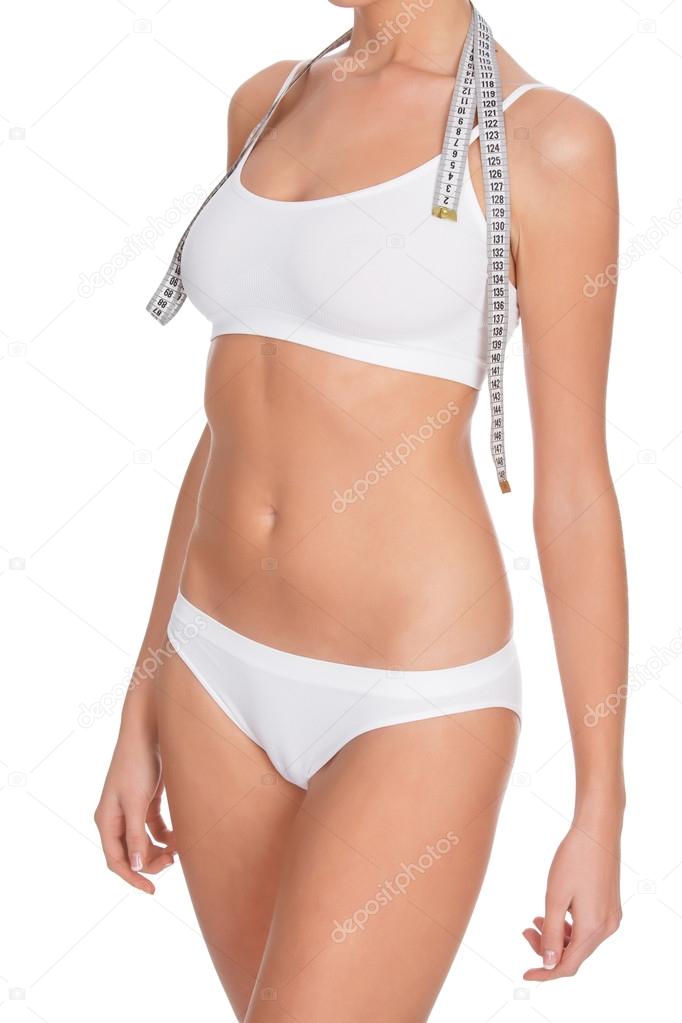 fit young woman measuring her waistline, white background