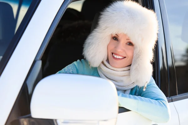 Donna felice con cappello di pelliccia bianca in macchina — Foto Stock