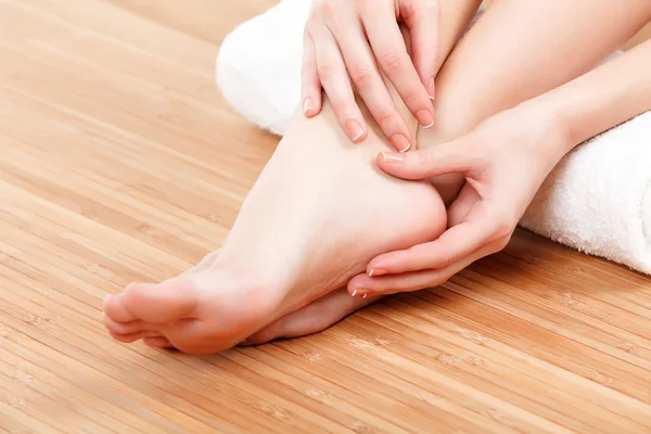 Female feet and hands with a white rolled towel — Stock Photo, Image