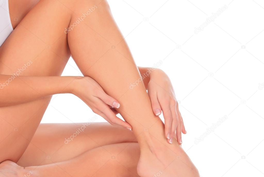 Woman sitting on the floor touches leg by hand