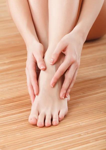 Belles mains et pieds féminins sur le sol en bois — Photo