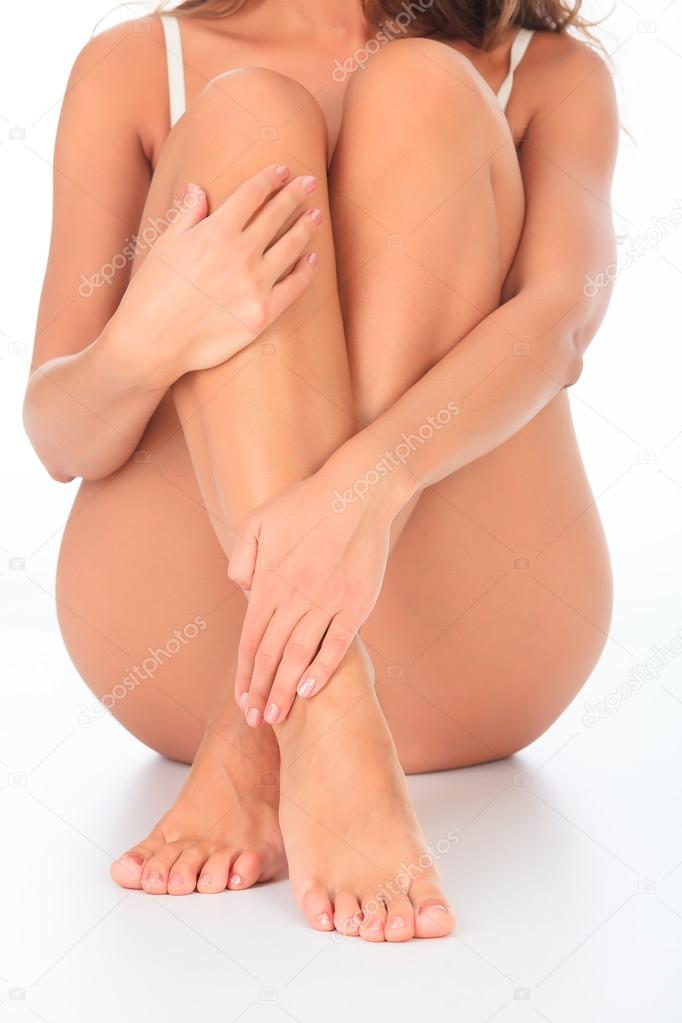 Woman sitting on the floor touches leg by hand