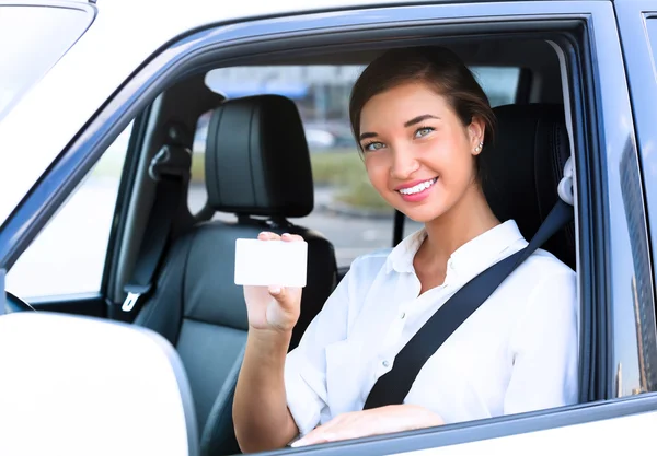 Девушка в машине, показывающая пустую белую карточку для вашего сообщения — стоковое фото