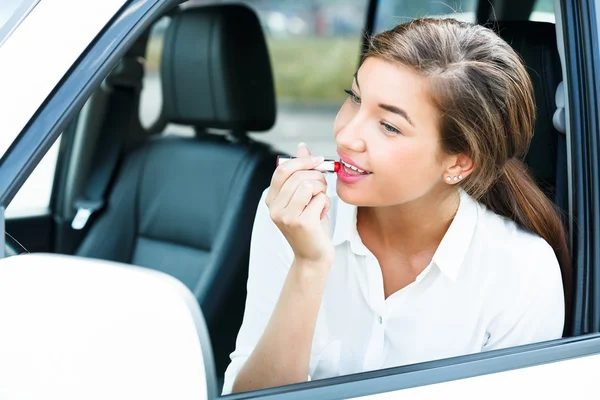 Mujer joven aplicando maquillaje mientras está en el coche — Foto de Stock