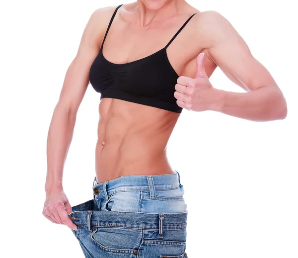 Kvinna visar sin viktminskning genom att bära en gamla jeans — Stockfoto