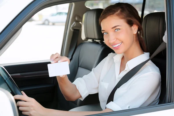 Κορίτσι σε ένα αυτοκίνητο που δείχνει μια κενή λευκή κάρτα για το μήνυμά σας — Φωτογραφία Αρχείου