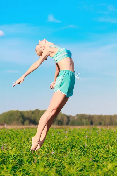 Mujer salta en un campo verde — Foto de Stock