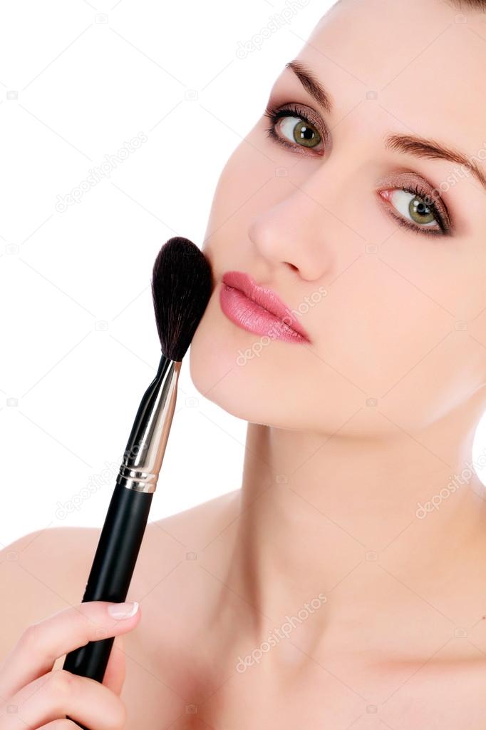 woman doing make-up on face with cosmetic brush