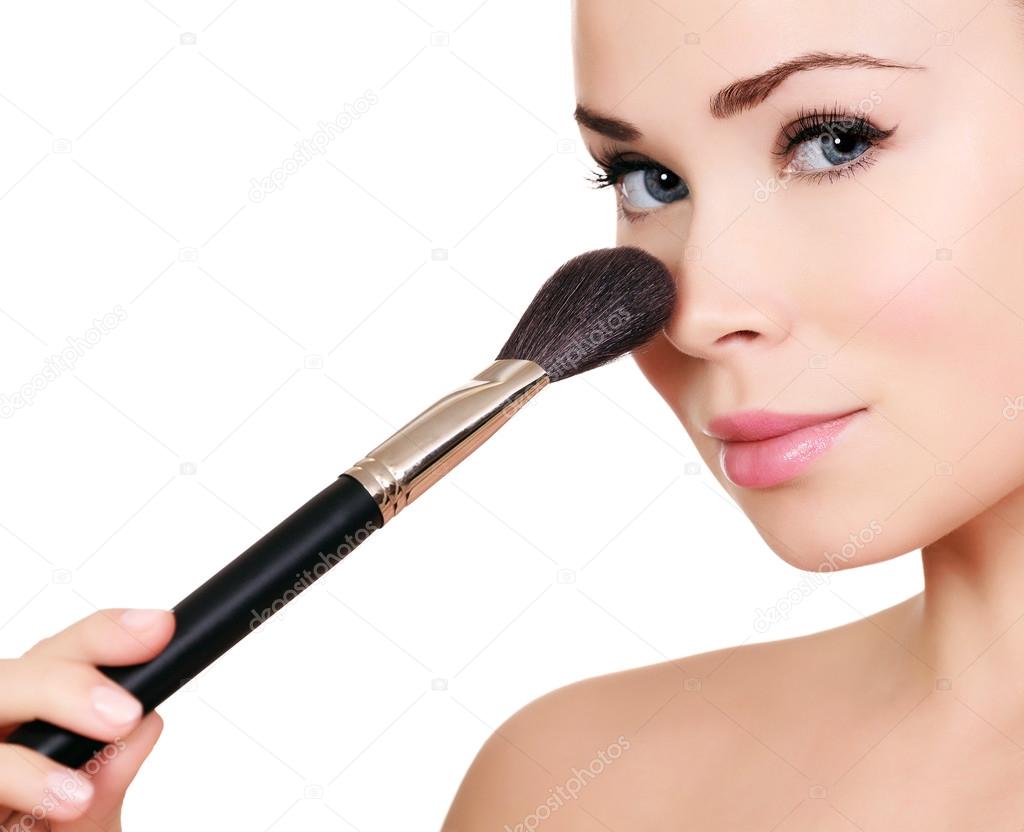 Beautiful woman doing make-up on face with cosmetic brush